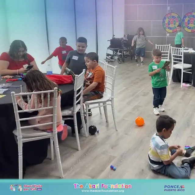 Niños juegan y hacen manualidades en el área infantil; al fondo hay una silla de ruedas y tableros de dardos.
